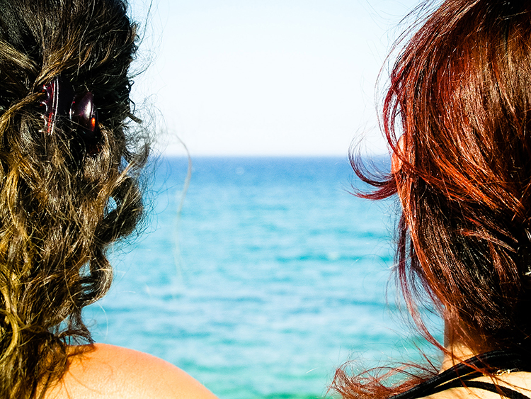 dos chicas observan juntas la tranquilidad del mar